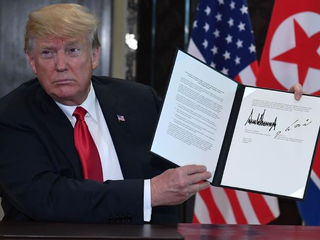 US President Donald Trump holds up the signed document.