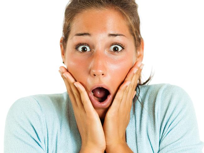 Shocked young gir with hands touching her face looking at camera, white background.