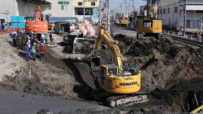 Excavators and rescue personnel work to construct a slope for rescue operations at the site where a truck on January 28 plunged into a sinkhole, trapping the vehicle's driver, in Yashio, Saitama Prefecture. Picture: AFP