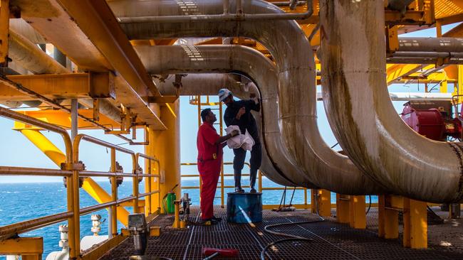 Workers clean oil leaks from pipes aboard an offshore oil platform in the Persian Gulf. Picture: Bloomberg