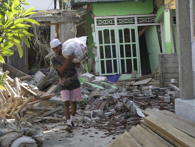 A villager carries his belonging from the ruin of his house in North Lombok. Picture: AP