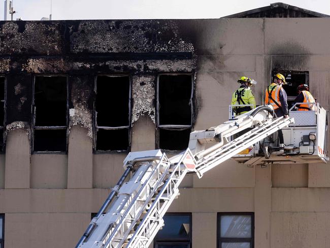 Firefighters inspect the Loafers Lodge hostel where a fire broke out a day earlier in the suburb of Newtown in Wellington on May 17, 2023. A fire ripped through a four-storey hostel in New Zealand's capital in the early hours of May 16, 2023, killing at least six people as others fled for their lives, with some plucked from the roof. (Photo by Marty MELVILLE / AFP)