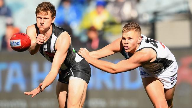 Will Hoskin-Elliott of the Magpies handballs while being tackled by Dan Houston of the Power. Picture: Quinn Rooney/Getty Images