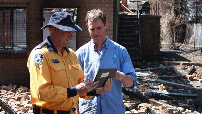 Justin Leonard assesses damage with a NSW Rural Fire Service officer after bushfires hit the Blue Mountains, 2013.