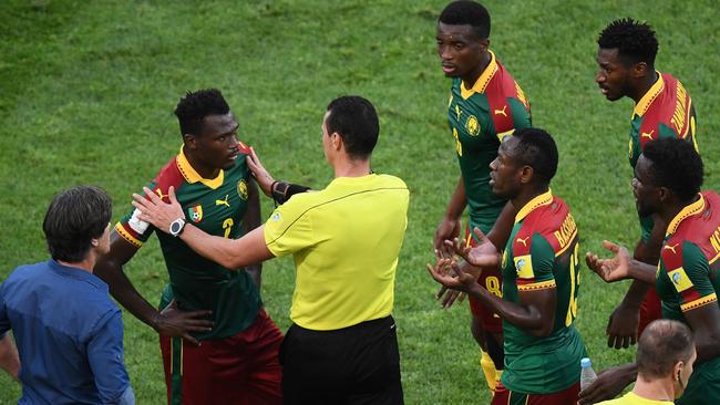 Colombian referee Wilmar Roldan (C) speaks to Cameroon's defender Ernest Mabouka (L)