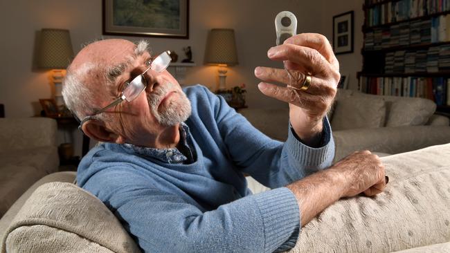 Dr John Rice did South Australia’s first child Cochlear implant and has one himself. Here, he is holding an original prototype. Picture: Tricia Watkinson