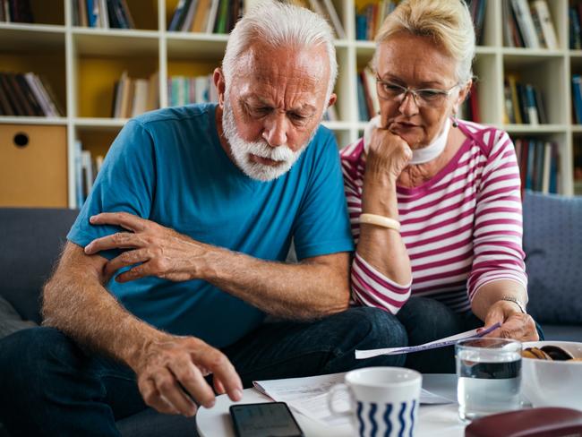 Worried senior couple is calculating their monthly expenses in the living room.