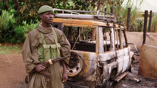 A Ugandan soldier standing by wreckage of burnt out vehicle destroyed during the tourist massacre in 1999. Picture: Supplied