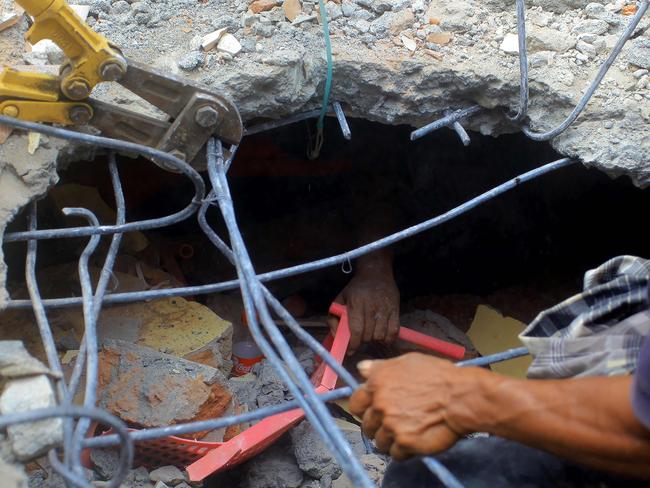 TOPSHOT - The hand of an earthquake survivor is seen under rubble as residents try to rescue him in Pidie Jaya, Aceh province on December 7, 2016. The death toll from a powerful earthquake that struck western Indonesia on December 7 has nearly doubled to 97, the military said, as more bodies were pulled from the rubble of scores of shattered buildings. / AFP PHOTO / AQIEN ABDULLAH