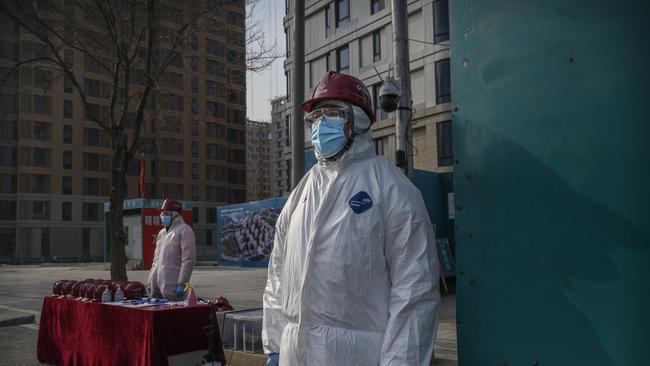 Chinese security guards wear protective suits as they guard the entrance next to buildings that will house athletes in the Beijing Winter Olympic Village. Picture: Getty