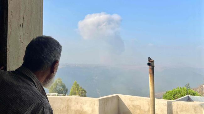 A man watches smoke billow after an Israeli airstrike in the southern Lebanese village of Qsair on Sunday. Picture: AFP