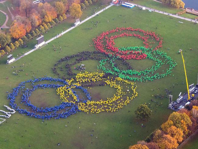 An aerial view shows thousands of people wearing colorful ponchos to form the Olympic rings to support Hamburg's bid for the Olympics 2024, in a park in Hamburg, Germany, Sunday Nov. 8, 2015. At left, protesters against Hamburg's Olympic bid laid the word "NO" next to the giant Olympic logo, but backers formed the letter W to turn the word into “NOW.” (Daniel Bockwoldt/dpa via AP)