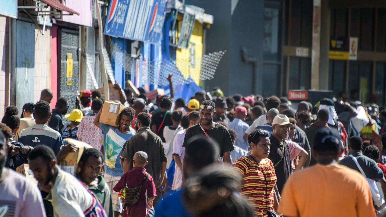 People carry items as crowds leave shops with looted goods amid a state of unrest in Port Moresby. Picture: AFP