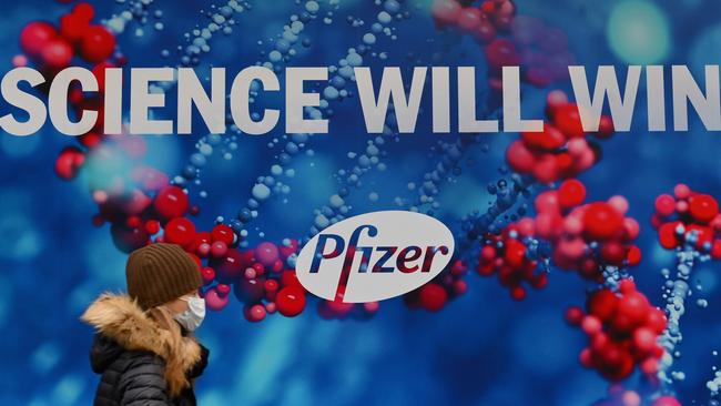 A person wearing a protective face mask walks past the Pfizer Inc. headquarters in New York City on December 9. Picture: Angela Weiss / AFP