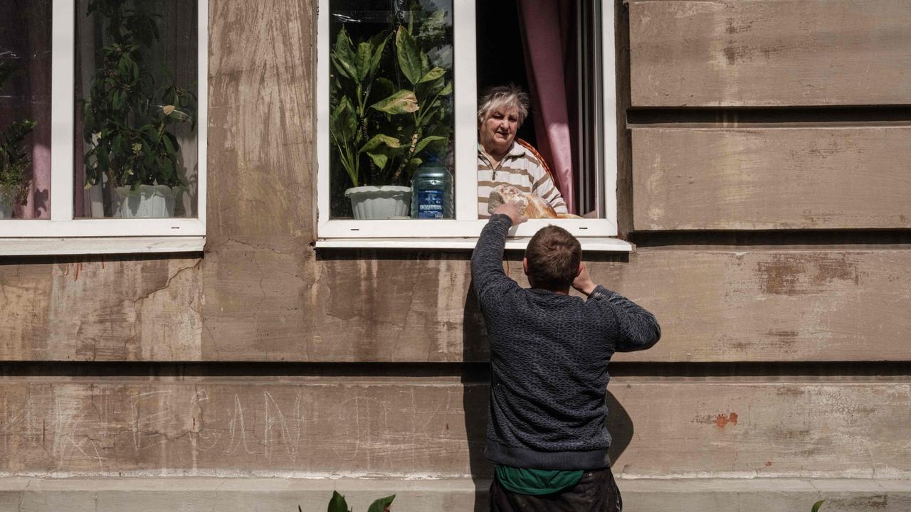 A man delivers loaves of bread to a woman as the eastern Ukraine city of Lyman received heavy shelling. Picture: Yasuyoshi CHIBA / AFP