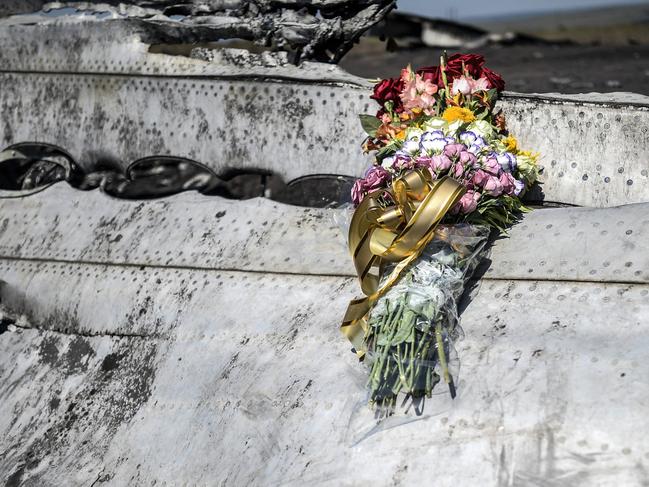 This photo taken on July 26, 2014 shows flowers, left by parents of an Australian victim of the crash, laid on a piece of the Malaysia Airlines plane MH17, near the village of Hrabove (Grabovo), in the Donetsk region. Ukraine sought on July 25 to avoid a political crisis after the shock resignation of its prime minister, as fighting between the army and rebels close to the Malaysian airliner crash site claimed over a dozen more lives. Dutch and Australian forces were being readied on July 26 for possible deployment to secure the rebel-held crash site of the Malaysia Airlines flight MH17 in east Ukraine where many victims' remains still lie nine days after the disaster claimed 298 lives. AFP PHOTO/ BULENT KILIC