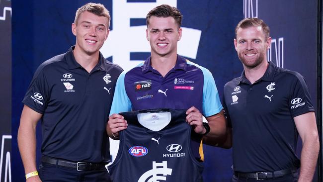 Brodie Kemp is presented with his Carlton jumper by Sam Docherty and Patrick Cripps.