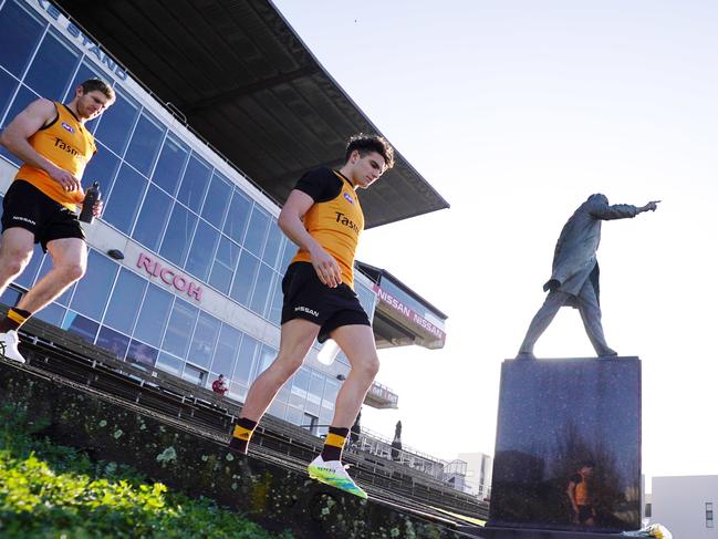 Hawks players walk past the John Kennedy Snr statue during an AFL Hawthorn Hawks training session at Waverley Park in Melbourne, Friday, June 26, 2020. Kennedy Snr,  who passed away yesterday, was a former Hawthorn player and premiership head coach and was known as the father of the club. (AAP Image/Michael Dodge) NO ARCHIVING