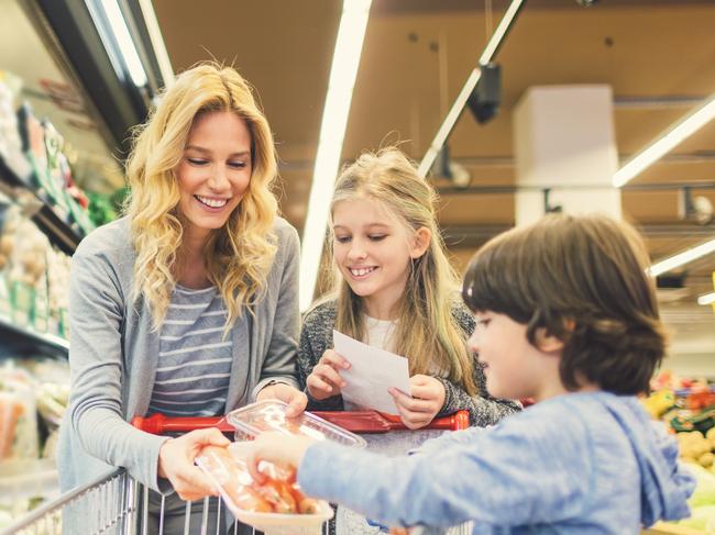 Mother with Son and Daughter In A Supermarket. Choosing groceries and putting in shopping chart