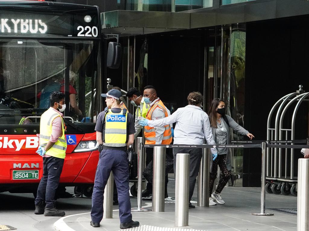 Recently arrived overseas travellers get off their bus and wait inside to check in at the Crown Promenade Hotel in Melbourne on Sunday. Picture: AAP/Scott Barbour