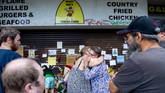 Emotional locals hug at the vigil for Hoa Tek Chiem and his wife Heang Kim Gau, who were murdered at their takeaway store Buzzy Bees. Picture: Jeremy Piper