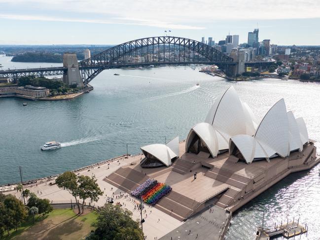 Sydney WorldPride.SYDNEY, AUSTRALIA - JUNE 24: In this aerial view, a group of people form a progress flag at the Sydney Opera House on June 24, 2022 in Sydney, Australia. 1,000 Sydneysiders united on the steps of the Sydney Opera House to form a giant human Progress Flag to launch Sydney WorldPride 2023 and commemorate the 44th anniversary of the first Sydney Gay and Lesbian Mardi Gras. Sydney WorldPride will take place from 17 February to 5 March 2023, celebrating Australia's fabulous and creative LGBTQIA+ community with more than 300 events taking place throughout Sydney, a city renowned for its diversity, inclusivity and proud LBGTQIA+ population. (Photo by James D. Morgan/Getty Images for Destination New South Wales)