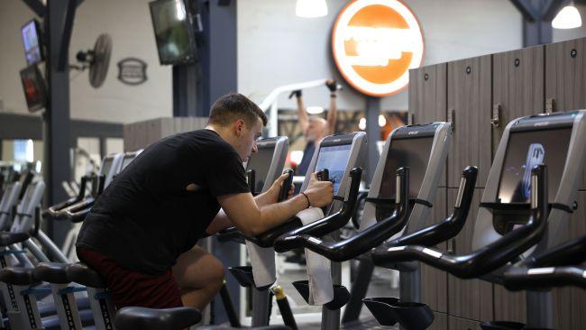 SAN FRANCISCO, CALIFORNIA - OCTOBER 15: A Fitness SF customer rides a stationary bike without a face mask a Fitness SF gym on October 15, 2021 in San Francisco, California. The City and County of San Francisco has started to ease indoor mask mandates today that allows groups of up to 100 vaccinated people to go without masks at gyms, religious gatherings, college classes and offices.   Justin Sullivan/Getty Images/AFP == FOR NEWSPAPERS, INTERNET, TELCOS & TELEVISION USE ONLY ==
