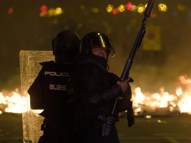 Anti-riot police officers stand guard in front of a barricade, which went up in flames. Picture: AFP