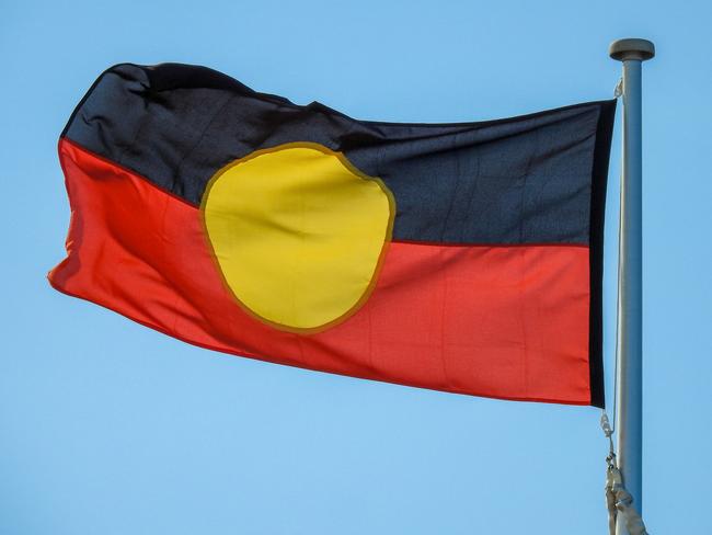 The Australian Aboriginal flag flies in the wind on a flagpole next to the Bondi Pavillion at Bondi Beach, Sydney. This image was taken on the windy and sunny afternoon of 2 February 2022.