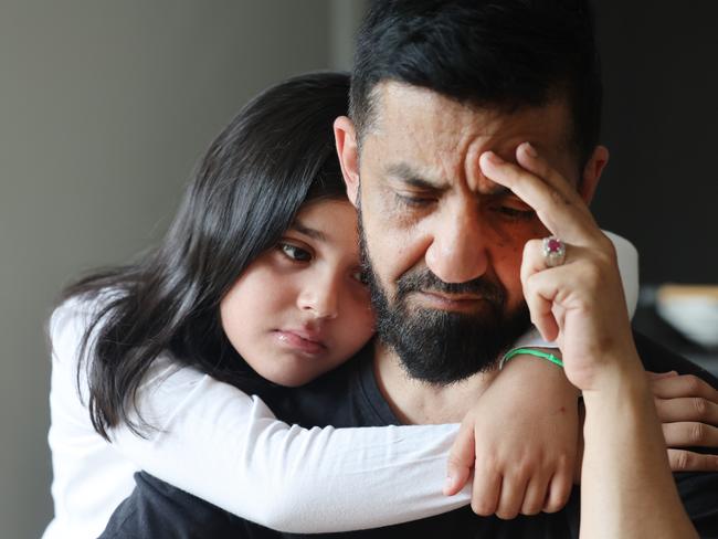 Zahra Popal 9 gives her father, Ahmad Popal, a hug at their Hope island home, while he speaks of losing his dream job thanks to an outsourced police check that took over two weeks to arrive. Picture Glenn Hampson