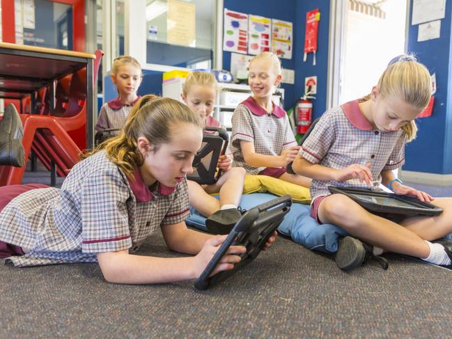 School girls using tablet computers for interactive online learning in the school classroom