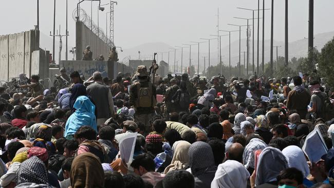 Afghans gather on a roadside near the military part of the airport in Kabul. Photo: Wakil KohsharAFP