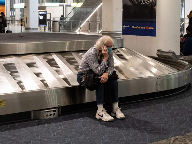 A traveller sits in baggage claim at LaGuardia Airport in New York, as airlines, struggle with the Omicron variant thinking airline staff leading to cancellations. Picture: AFP