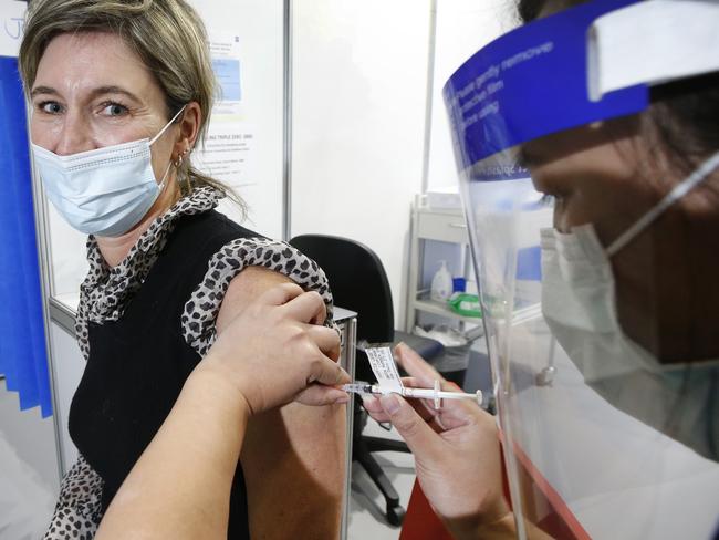 Crowds flock to vaccine hubs to get the jab after the COVID lockdown was announced at the Melbourne Exhibition Centre. Dr Georgina Baker 46, gives a smile as she gets her vaccine.                         Picture: David Caird