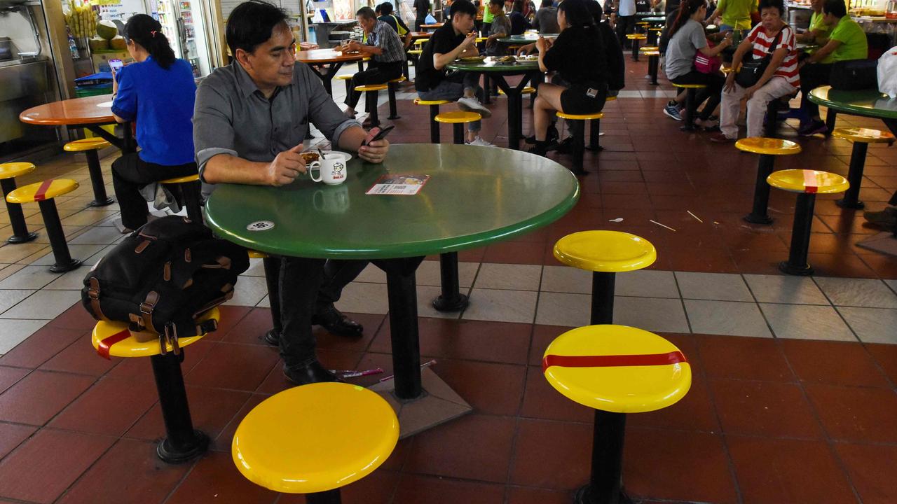 Customers take their meal while some chairs are marked with red tapes as authorities implement social distancing at a hawker centre in Singapore. Picture: AFP