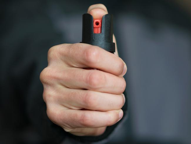 Man holding pepper spray (tear gas) in his hand. Self-defense. Blur background, close up.