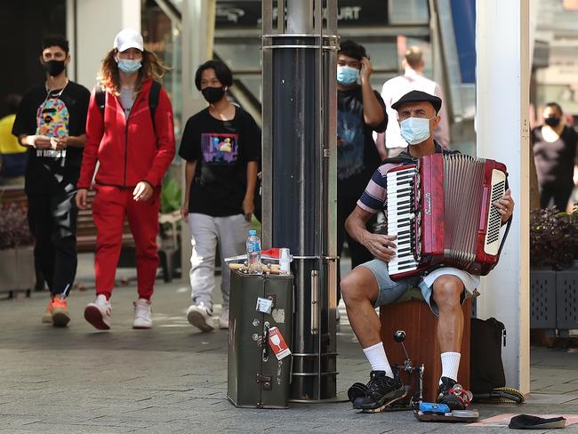 A busker plays his piano accordion wearing his face mask in Perth’s Hay Street Mall. Life is going on much as always in the west. Picture: Paul Kane/Getty Images