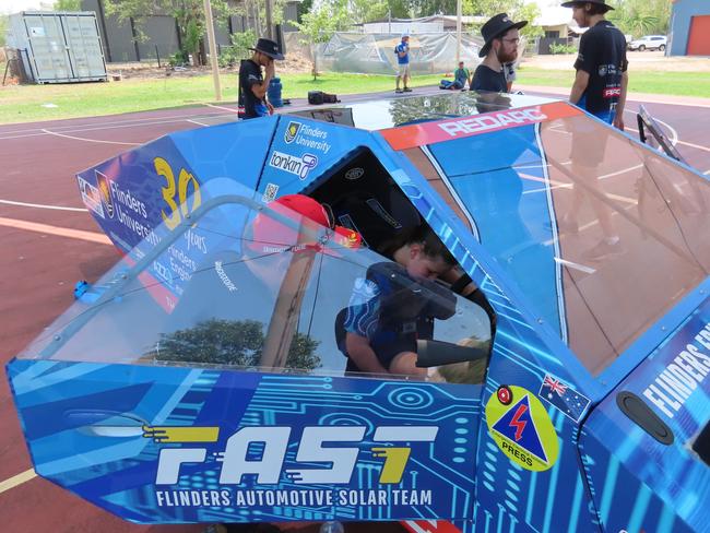 Flinders University team member helping Niamh turner strap in to the driver's seat of the solar powered car, Monday, October 16, 2023. Picture: Darcy Jennings.