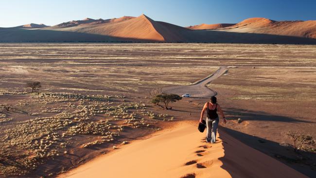 A woman walking up the ridge of sand dune in Southern Africa. Picture: Lonely Planet 