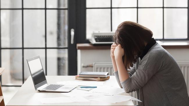 Tired business woman at workplace in office, holding her head in hands. Overworking, making mistake, stress, depression concept