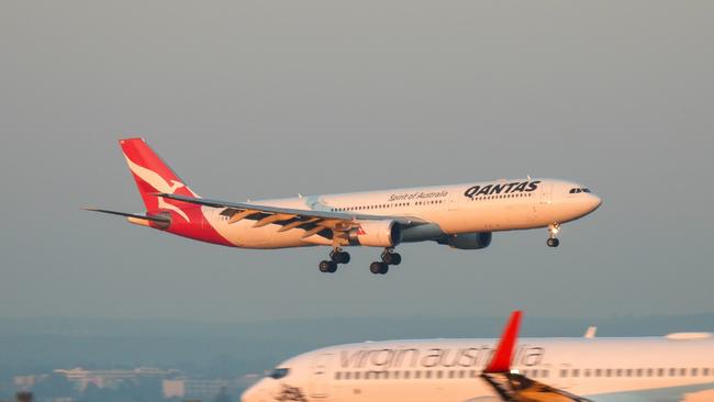 A Qantas Airbus A330-303 plane, registration VH-QPB, coming into land from the south on the main runway of Sydney Kingsford-Smith Airport as flight QF128 from Hong Kong. In the foreground is a Virgin Australia Boeing B737-8FE plane, registration VH-YFZ, taxiing before departure as flight VA1528 to Hobart.  This image was taken from Mill Stream Lookout, Botany Bay on a sunny morning at sunrise on 30 March 2024.27 October 2024Kendall HillPhoto - iStock