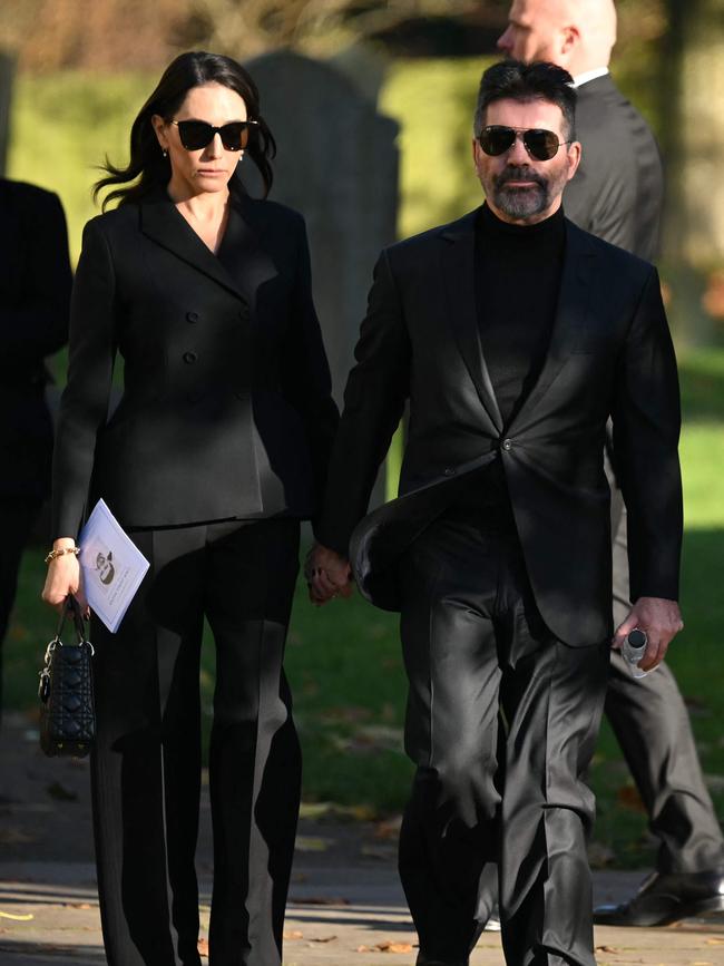 Simon Cowell (R) and Lauren Silverman leave after attending the funeral.