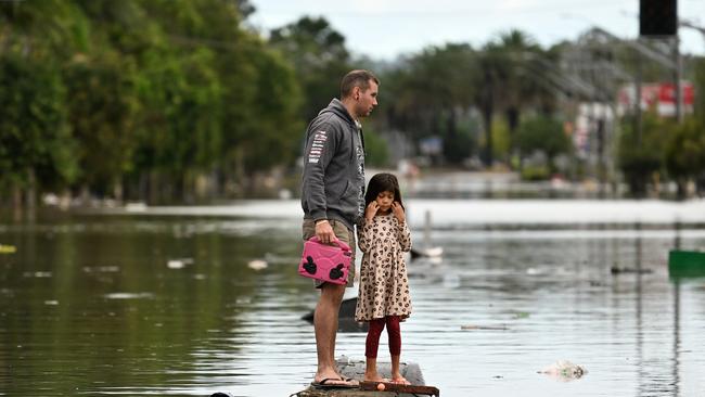 A father and his young daughter inspect a flooded street at Lismore in March. Picture: Dan Peled/Getty Images