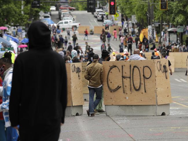 New cement and wood barricades bear the name CHOP, Tuesday, June 16, 2020, inside what has been named the Capitol Hill Occupied Protest zone in Seattle. The city put the barriers in place Tuesday in hopes of defining an area where emergency, delivery, and other vehicles can travel through the area while still preserving space for protesters, who have been there since police pulled back from near the department's East Precinct after recent clashes with people protesting the death of George Floyd. (AP Photo/Ted S. Warren)