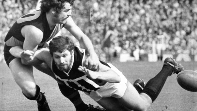 Port Adelaide goal sneak Randall Gerlach is tackled by Glenelg defender Rex Voigt.]