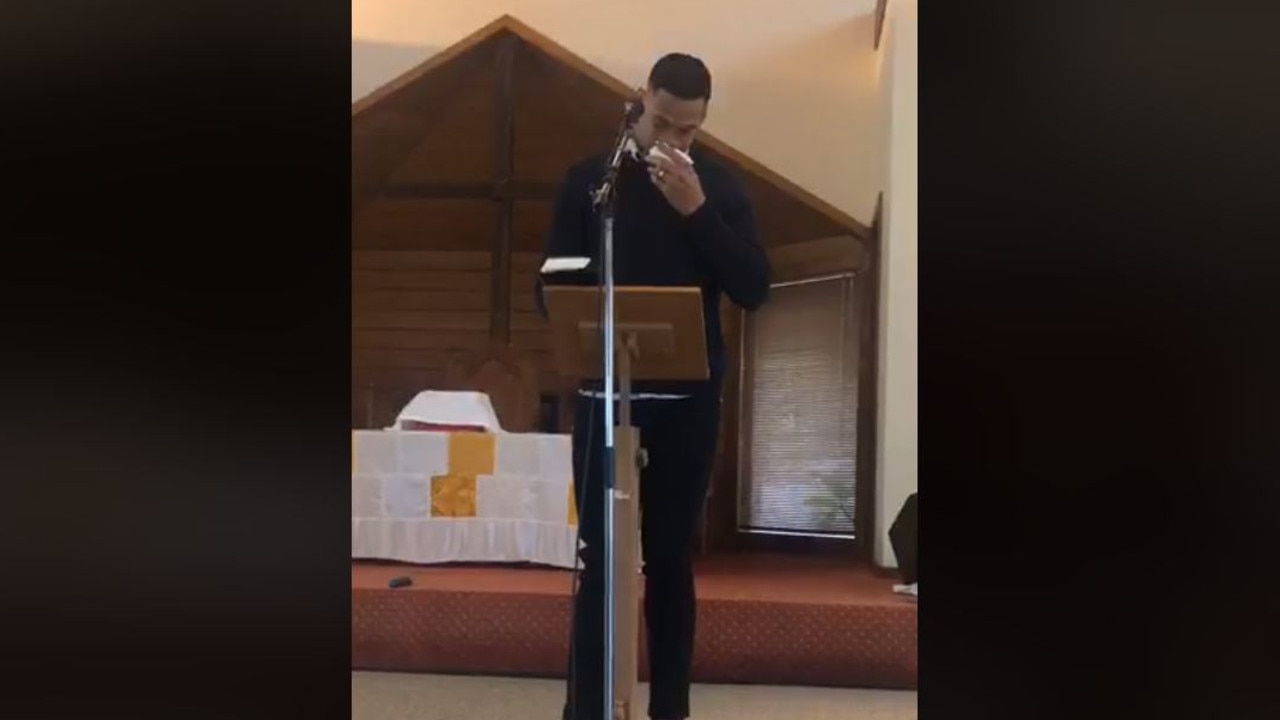 Israel Folau wipes his eyes with a tissue while preaching at his church.