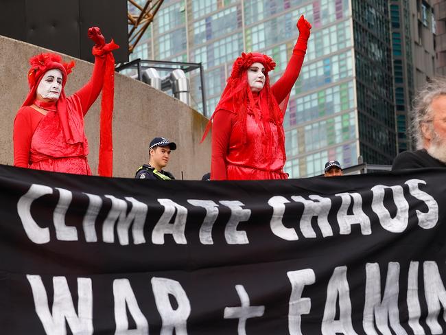 An Extinction Rebellion protester scales the Victorian Arts Centre in Melbourne to protest on climate change as other protesters gather at the base. Picture: Ian Currie