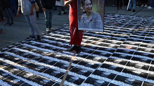 An activist holds a portrait of Aung San Suu Kyi while surrounded by images of Myanmar's military general Min Aung Hlaing outside the United Nations University building in Tokyo on Monday. Picture: AFP