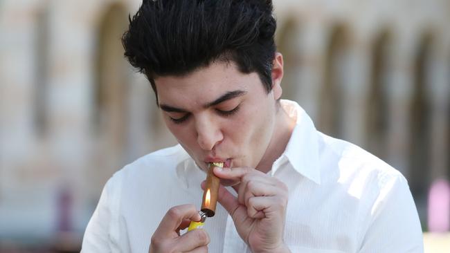 Drew Pavlous smokes a “victory cigar” at the University of Queensland on Monday. Picture: Annette Dew