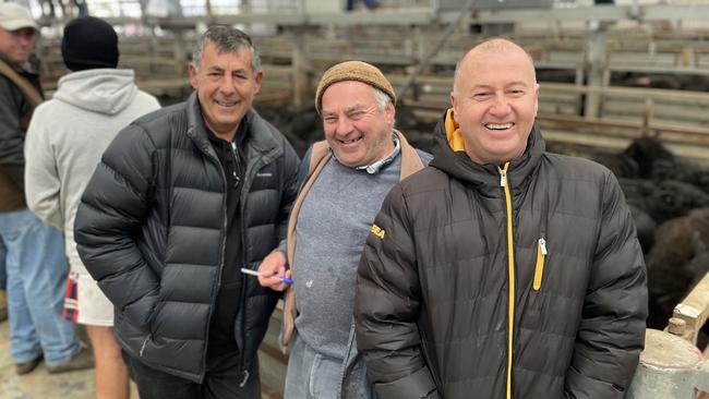 Friends Terry Tairovski, left, and Peno Huseni, right, bought 35 Angus heifer calves for $1210 at the Pakenham store sale. They are pictured with their agent Wayne Barker, centre.